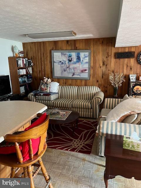 living room featuring wood walls and a textured ceiling