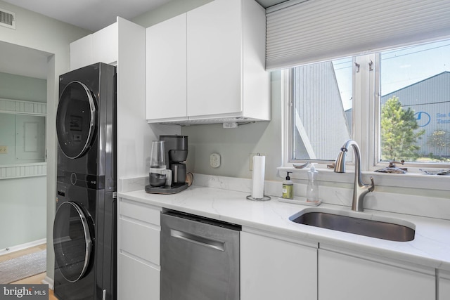 kitchen with stainless steel dishwasher, sink, white cabinets, and stacked washer / dryer