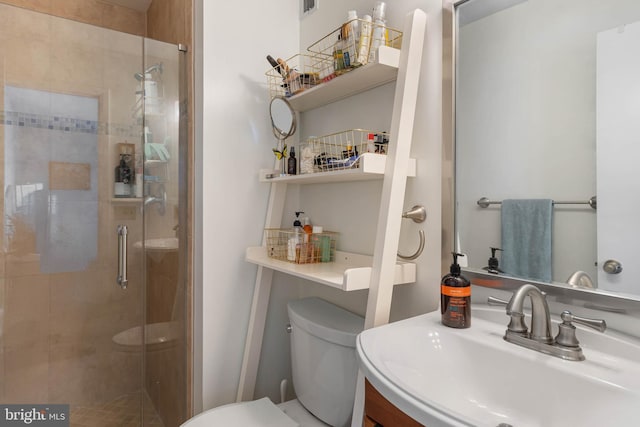 bathroom with sink, a shower with shower door, and toilet