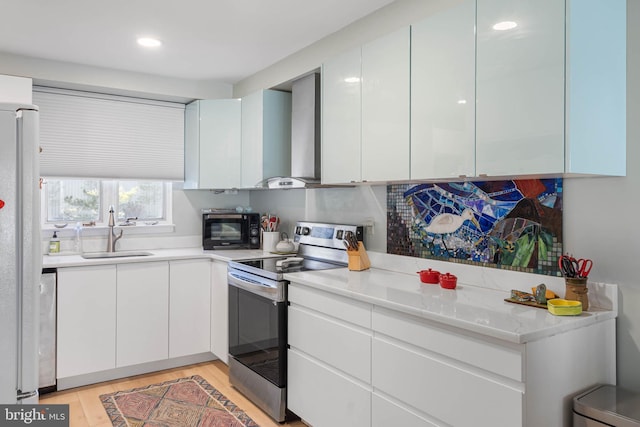 kitchen with wall chimney exhaust hood, stainless steel appliances, sink, white cabinets, and light hardwood / wood-style floors