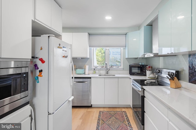 kitchen featuring appliances with stainless steel finishes, light hardwood / wood-style flooring, white cabinetry, and sink