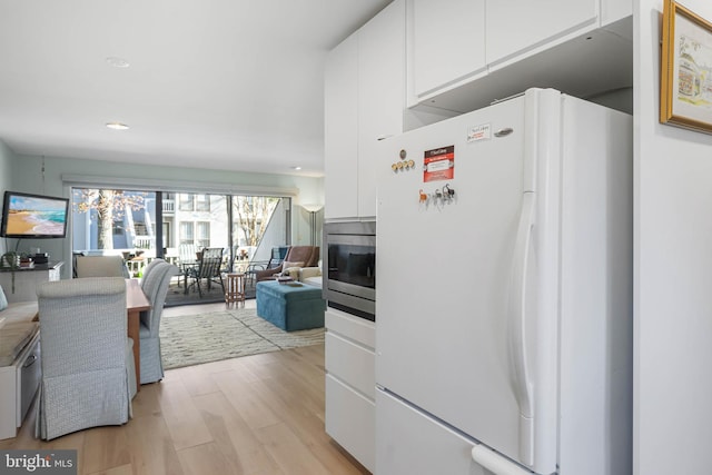 kitchen featuring white cabinets, white fridge, stainless steel microwave, and light hardwood / wood-style floors