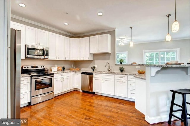 kitchen with white cabinets, pendant lighting, stainless steel appliances, and a breakfast bar area