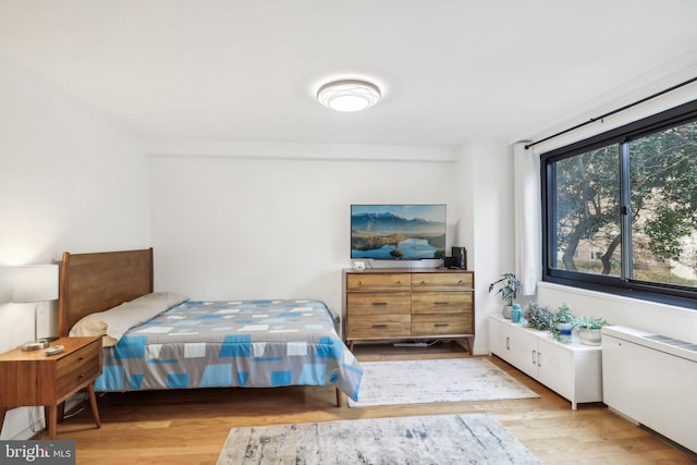 bedroom featuring radiator heating unit and light hardwood / wood-style flooring