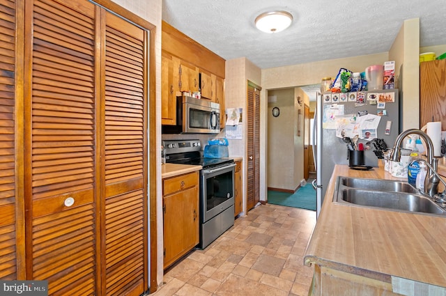 kitchen with appliances with stainless steel finishes, a textured ceiling, and sink