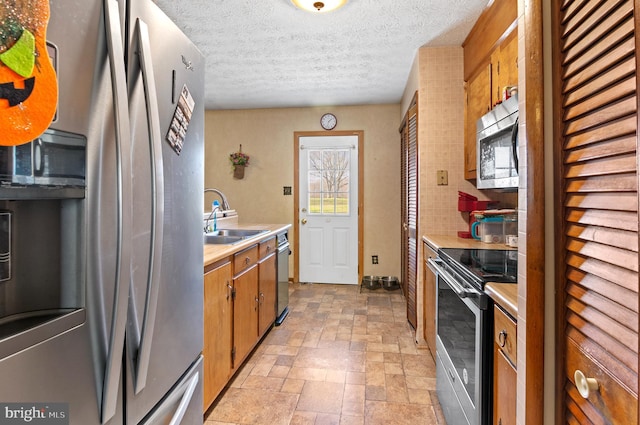 kitchen with sink, a textured ceiling, and appliances with stainless steel finishes