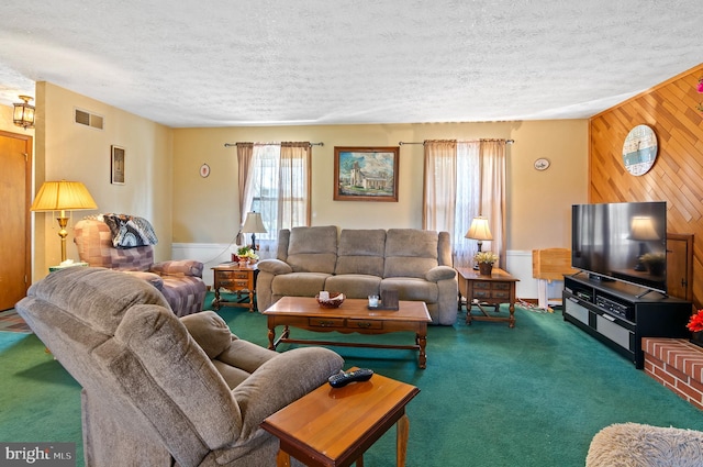 living room featuring carpet flooring, wooden walls, and a textured ceiling