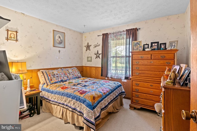 carpeted bedroom with a textured ceiling and wooden walls