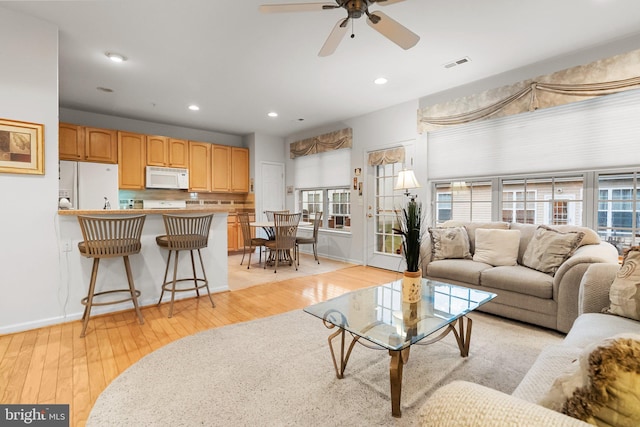 living room with ceiling fan and light hardwood / wood-style flooring