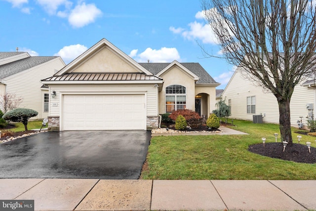 view of front of home with cooling unit, a garage, and a front lawn