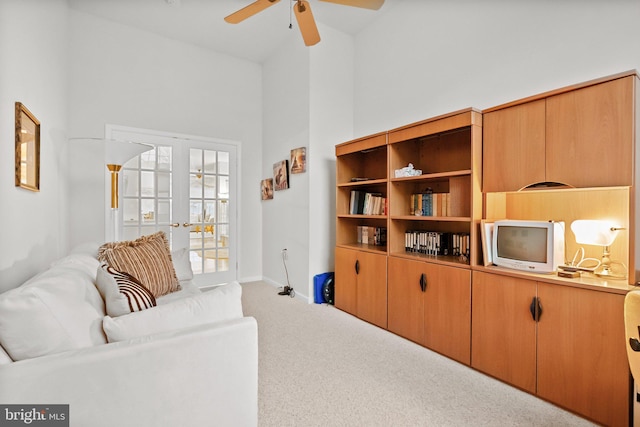 carpeted living room featuring ceiling fan, high vaulted ceiling, and french doors