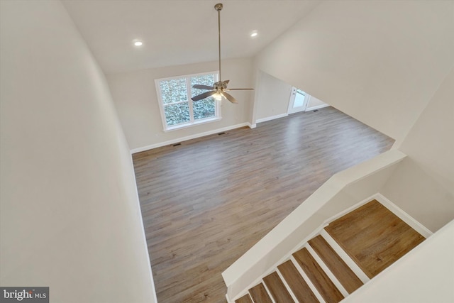 stairs with hardwood / wood-style flooring, ceiling fan, and lofted ceiling