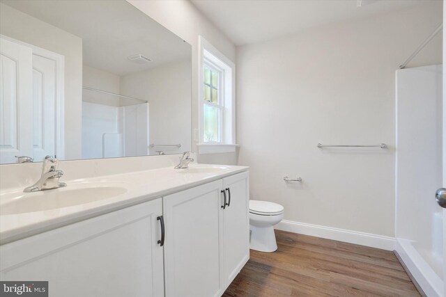 bathroom featuring vanity, hardwood / wood-style flooring, toilet, and walk in shower