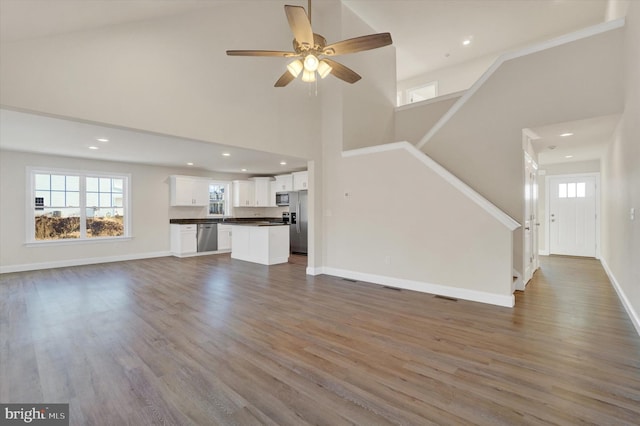 unfurnished living room featuring dark hardwood / wood-style floors, ceiling fan, and high vaulted ceiling