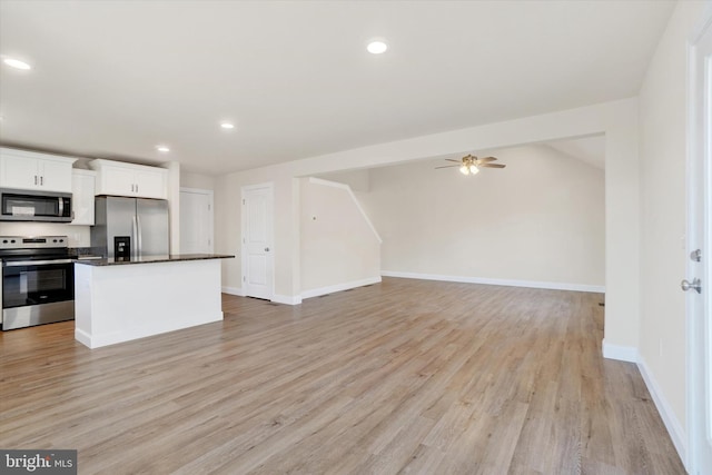 kitchen with white cabinets, stainless steel appliances, a kitchen island, and light hardwood / wood-style floors