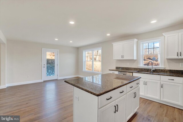 kitchen with white cabinetry, sink, a center island, and dark stone counters