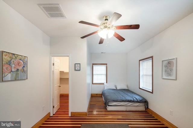 bedroom with a closet, a walk in closet, hardwood / wood-style flooring, and ceiling fan