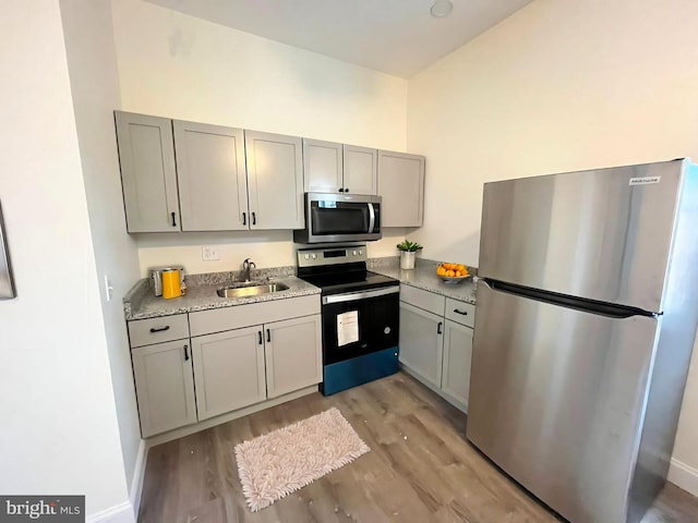 kitchen with gray cabinetry, sink, light wood-type flooring, and appliances with stainless steel finishes