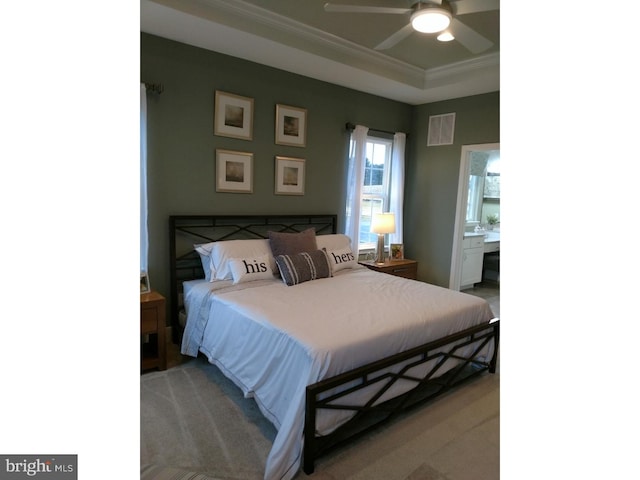 bedroom with carpet flooring, ensuite bathroom, a tray ceiling, ceiling fan, and crown molding