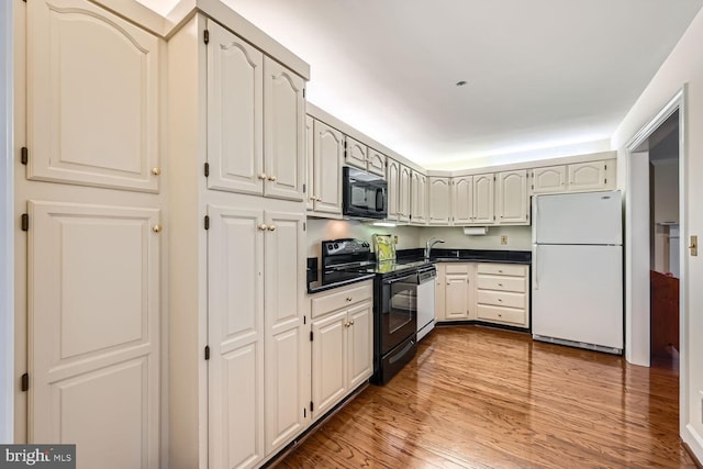 kitchen featuring black appliances, sink, and light hardwood / wood-style flooring