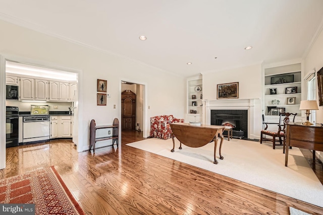 living room featuring a brick fireplace, hardwood / wood-style flooring, built in features, and ornamental molding