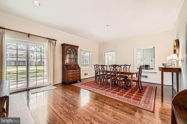 dining space with hardwood / wood-style floors and ornamental molding