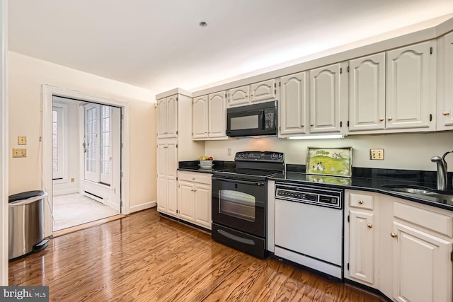 kitchen with sink, light wood-type flooring, white cabinets, and black appliances