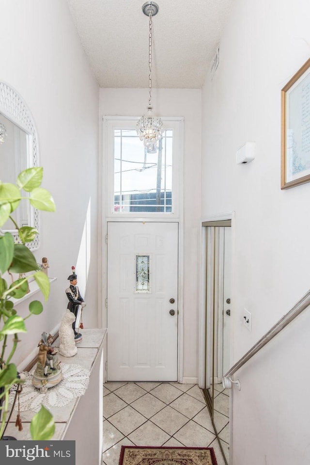 tiled foyer with a textured ceiling and a notable chandelier