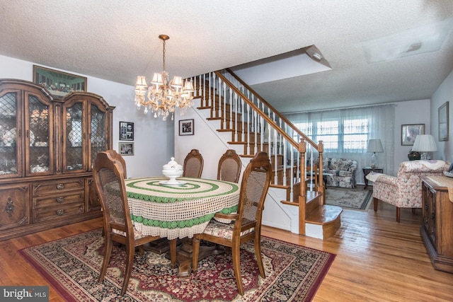 dining room featuring a textured ceiling, light hardwood / wood-style flooring, and a notable chandelier