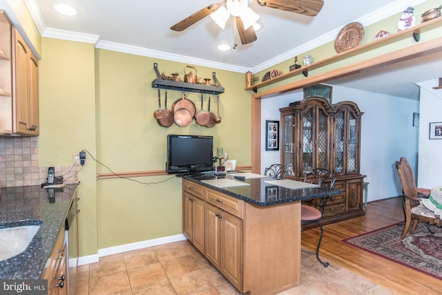 kitchen with kitchen peninsula, tasteful backsplash, dark stone countertops, light hardwood / wood-style floors, and a breakfast bar area