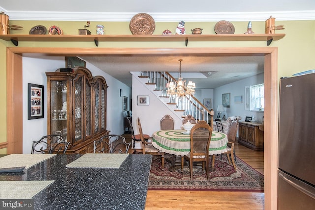 dining area featuring hardwood / wood-style floors, ornamental molding, and an inviting chandelier