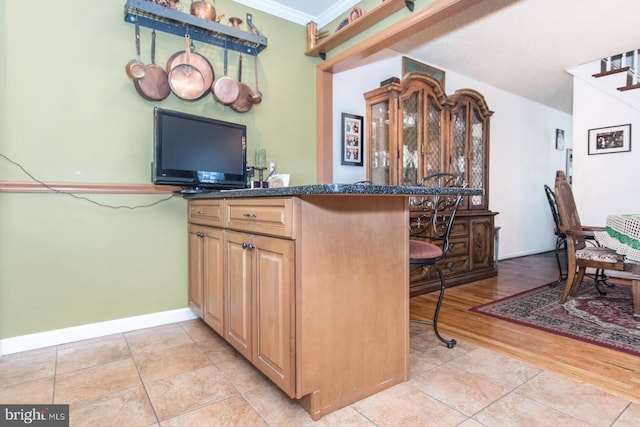 kitchen with a breakfast bar area, kitchen peninsula, crown molding, and light hardwood / wood-style floors