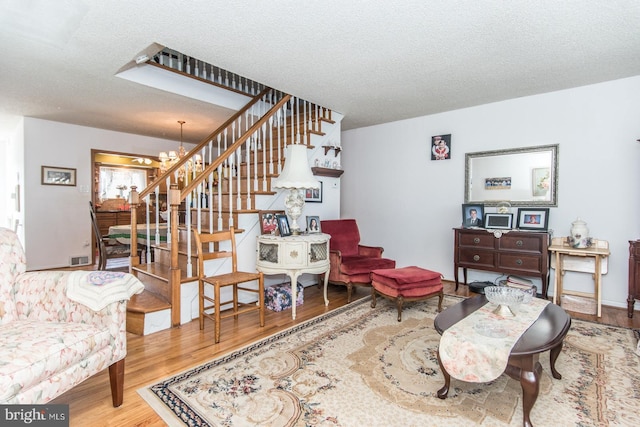 living room with hardwood / wood-style floors, a textured ceiling, and an inviting chandelier