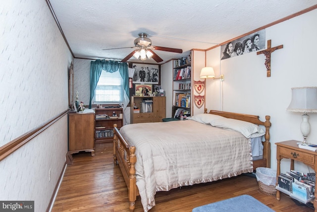 bedroom featuring a textured ceiling, dark hardwood / wood-style floors, ceiling fan, and crown molding