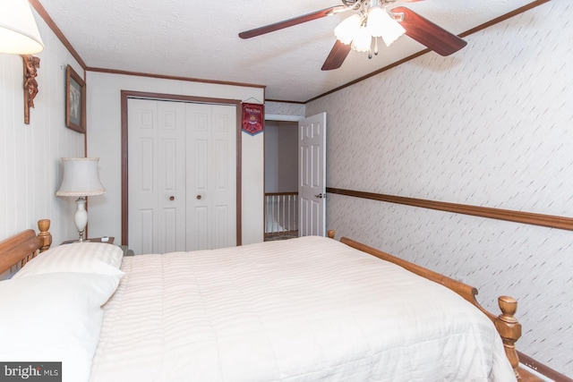 bedroom featuring a textured ceiling, a closet, ornamental molding, and ceiling fan