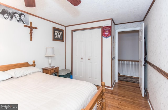 bedroom with a textured ceiling, ceiling fan, crown molding, hardwood / wood-style floors, and a closet