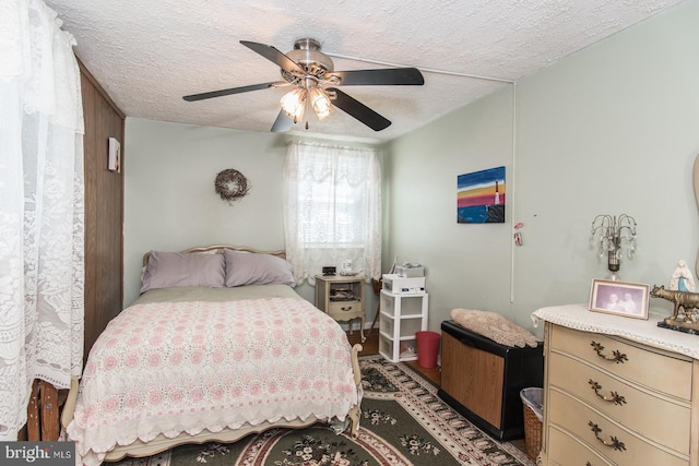 bedroom featuring ceiling fan, dark hardwood / wood-style flooring, and a textured ceiling