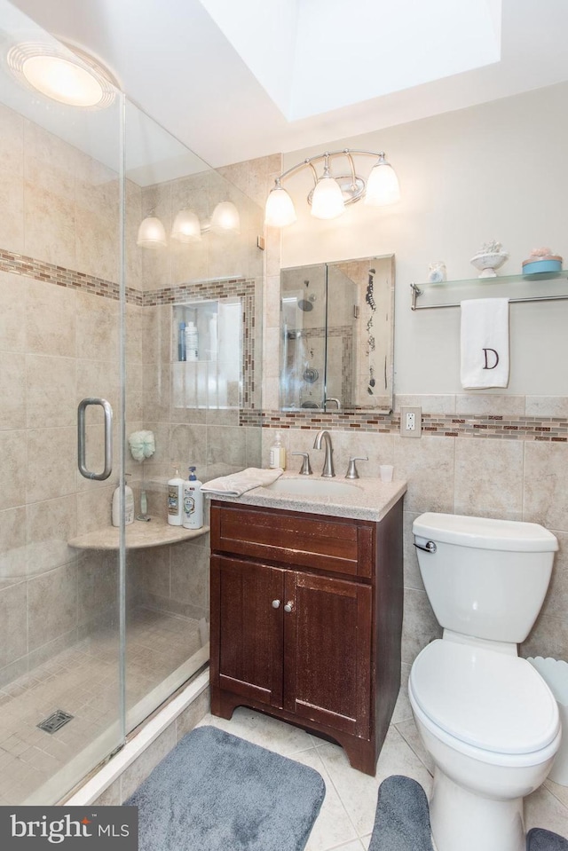 bathroom with tile patterned floors, vanity, tile walls, and walk in shower