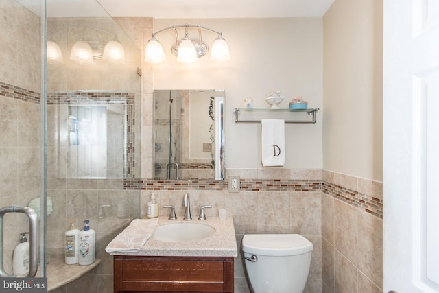 bathroom featuring walk in shower, vanity, toilet, and tile walls