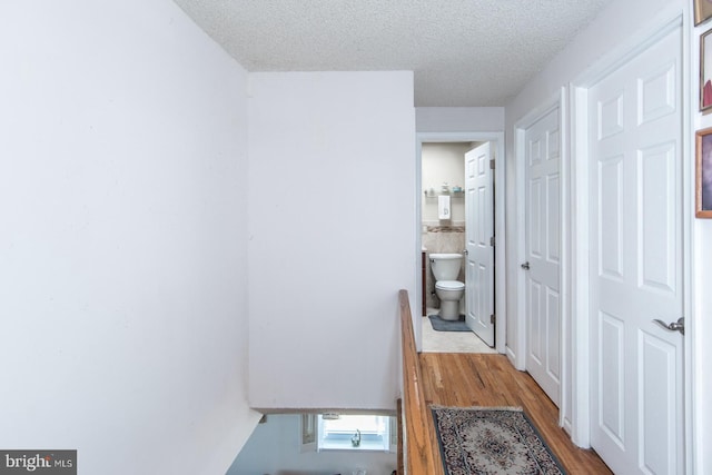 hall with a textured ceiling and light wood-type flooring