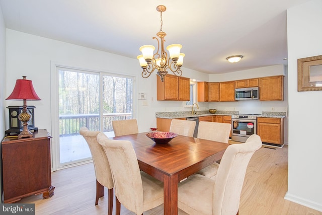 dining space with sink, light hardwood / wood-style floors, and a notable chandelier