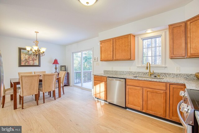 kitchen with pendant lighting, sink, appliances with stainless steel finishes, light hardwood / wood-style floors, and light stone countertops