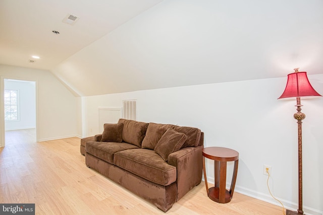 living area with light wood-type flooring and vaulted ceiling