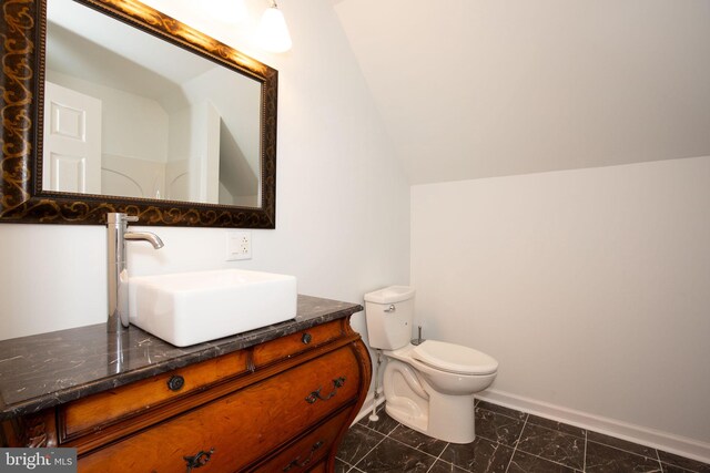 bathroom featuring vanity, toilet, and vaulted ceiling