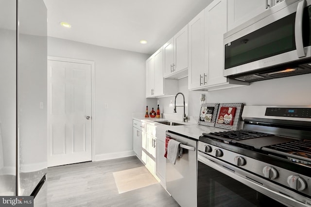 kitchen with white cabinetry, light hardwood / wood-style flooring, stainless steel appliances, and sink