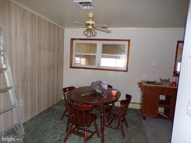 carpeted dining area with ceiling fan and crown molding