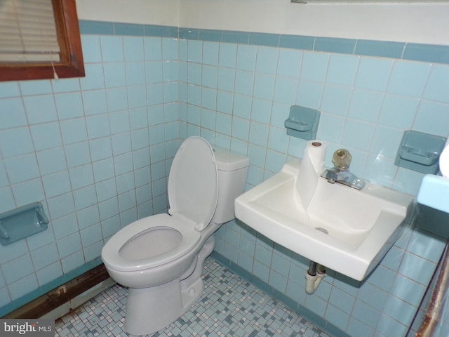 bathroom featuring toilet, tile patterned floors, tile walls, and sink