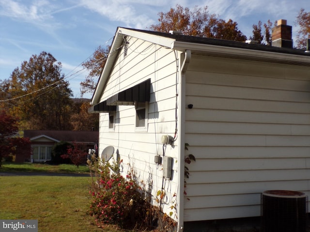 view of side of home with central AC and a lawn