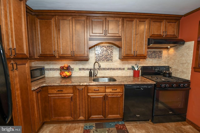 kitchen featuring tasteful backsplash, light stone countertops, sink, and black appliances