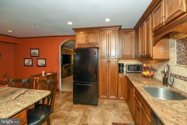 kitchen with sink, a kitchen breakfast bar, light stone counters, decorative backsplash, and appliances with stainless steel finishes